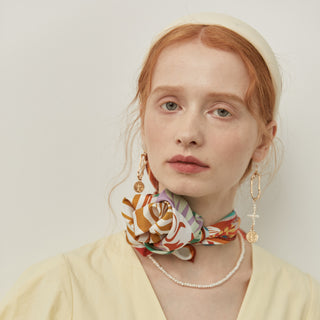 Silk bandana styled as neck accessory featuring zebra print with vibrant botanical patterns in orange, white, and green tones against light background