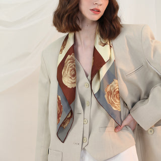 Woman wearing Berlin Rose silk scarf – 65cm vintage floral square bandana in sepia tones, styled over a beige blazer.