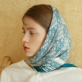 Teal Heritage Grace silk scarf worn as headscarf, featuring intricate geometric and floral patterns with white background and elegant turquoise design