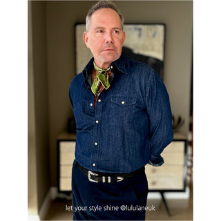 Styling example: green men's silk neckerchief with beige paisley pattern worn with blue denim shirt in indoor setting