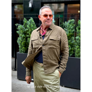 Styling example: burgundy men's silk neckerchief with beige paisley pattern worn with khaki workwear style shirt in outdoor setting