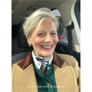 Navy blue paisley silk scarf styled as a neckerchief with a tan coat and green sweater, showcasing the versatile unisex design