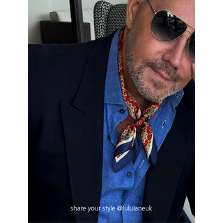 Red and navy paisley silk neckerchief styled with blue shirt and navy blazer, showcasing elegant men's accessory with classic pattern