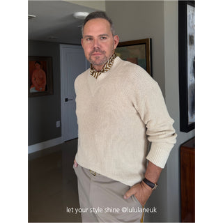 Styling example: bronze men's silk scarf with classic striped pattern worn with creamy white knitted sweater in indoor setting