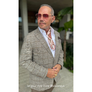 Stylish silk neckerchief with geometric pattern worn with light gray blazer and white shirt, accessorized with pink aviator sunglasses