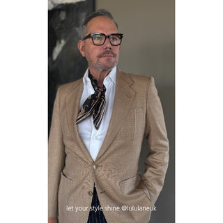 Stylish dark patterned silk neckerchief worn with tan blazer and white shirt, demonstrating elegant men's accessory styling