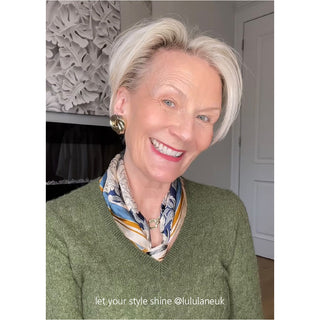 Silk peony scarf styled as elegant neck accessory with blue and beige floral pattern, paired with green sweater for sophisticated look