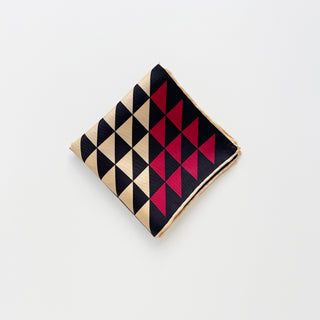 Folded beige and black silk bandana with red accent and geometric triangle print.