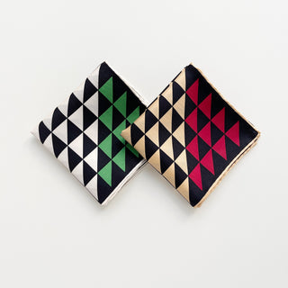 Two folded silk bandanas with geometric triangle print-one in black, white and green, the other is in black, beige and red.