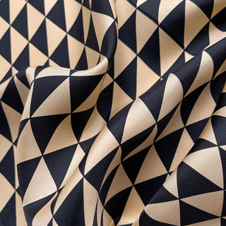 Close-up of a beige and black geometric triangle silk bandana.