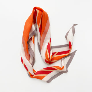 Cashmere wool silk scarf in orange, red, taupe, and cream with bold geometric stripes.