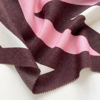 Close-up of a cashmere wool silk scarf in brown, white and pink with herringbone stripes.