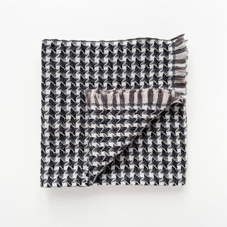 Folded cashmere scarf in taupe, black and cream white with houndstooth check pattern on a light grey background