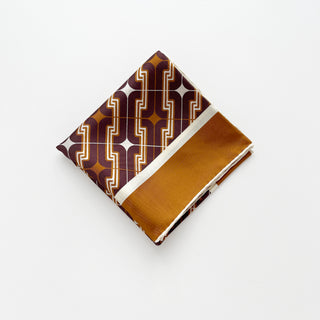 Folded men's luxury silk scarf featuring geometric burgundy and brown pattern with cream white hand-rolled edges