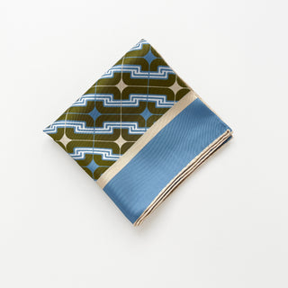 Folded men's luxury silk square scarf featuring retro geometric pattern in dusty blue & olive green colour way with hand-rolled edges. 