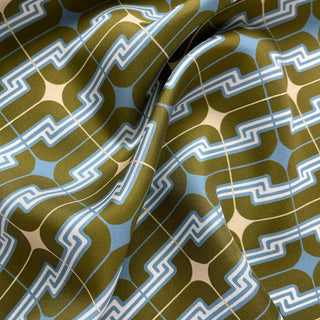 Close-up of a men's luxury silk square scarf featuring retro geometric pattern in dusty blue, olive green and cream white.