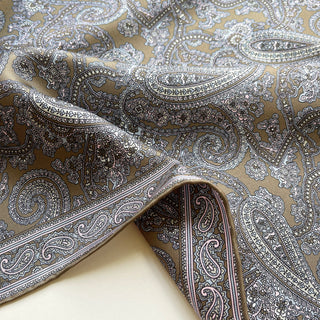 Close-up of taupe paisley silk neckerchief showing smooth twill texture and fine hand-rolled edges.