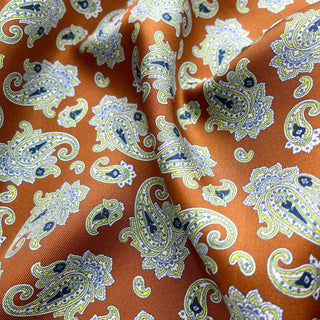 Close-up of a honey brown paisley men’s silk neckerchief scarf – luxurious silk twill fabric with blue, white and yellow paisley pattern