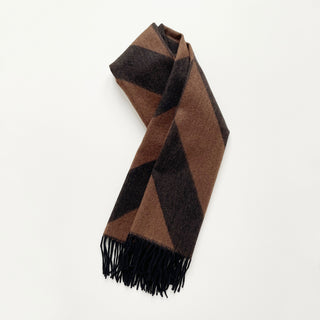 Brown and black herringbone cashmere scarf with fringed edges on light grey background.