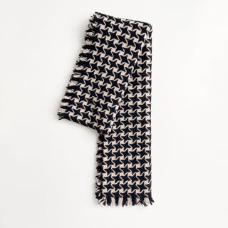 Folded pure cashmere scarf in black and beige with houndstooth check pattern on a light grey background