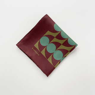 Folded geometric mid-century silk scarf by LuluLane with Bauhaus-inspired design in chocolate brown and teal green tones showcasing the meticulous hand-rolled hems.