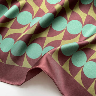Close-up of geometric mid-century silk scarf by LuluLane with Bauhaus-inspired design in chocolate brown and teal green tones showcasing the meticulous hand-rolled hems.