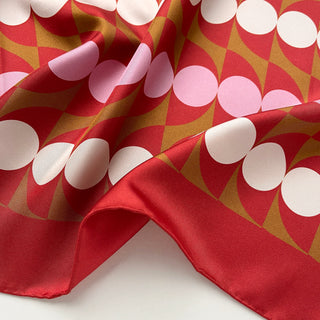 Close-up of geometric mid-century silk scarf by LuluLane with Bauhaus-inspired design in red, pink and brown tones showcasing the meticulous hand-rolled hems.