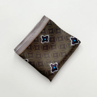 Folded olive green silk neckerchief with geometric diamond pattern and decorative star motifs with blue centers, displaying a gray border edge