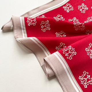 Vibrant red silk square scarf with white crown pattern throughout, bordered by elegant beige trim with white stripes, displayed on white surface.
