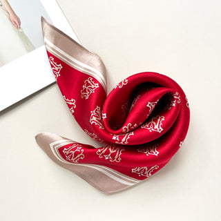 Vibrant red silk square scarf with white crown pattern, featuring taupe border trim, elegantly draped to showcase its luxurious sheen and design