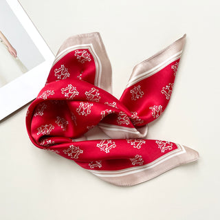 Red silk square scarf with decorative crown pattern, featuring beige border trim and elegant sheen, displayed folded against white background
