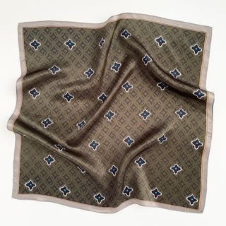 Olive green silk neckerchief with geometric background pattern and star-like black motifs with blue centers, bordered by a light taupe trim