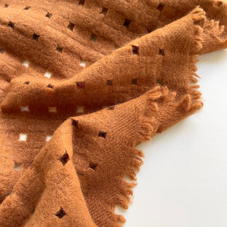 Close-up of a burnt mustard pure cashmere scarf featuring openwork jacquard design.