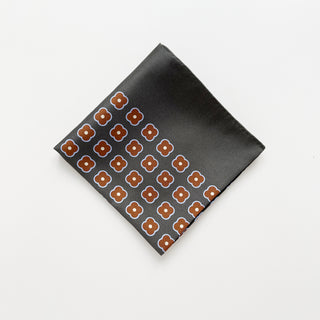 Folded lead grey silk square scarf by LuluLane with rust red four-petal flower motif, double-sided print and hand-rolled hems.