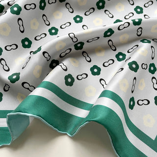 Silk scarf with light grey background featuring teal green flowers and black chain links pattern, bordered with teal green stripes
