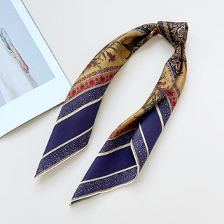 Folded indigo silk neckerchief with gold, red floral pattern and geometric borders, displaying luxurious vintage design on white background