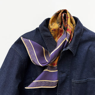 Indigo Royal Vintage Bloom silk scarf with purple, gold and red floral patterns elegantly styled on dark denim jacket, showcasing hand-rolled edges