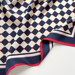 Close-up of a unisex silk scarf 65cm chess board design in navy and ivory with red accents, double-sided silk, hand-rolled edges by LuluLane.