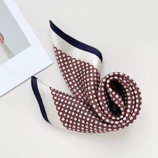 Red silk scarf with modern lattice pattern, featuring navy blue border and cream background, elegantly draped to showcase luxurious sheen and texture.