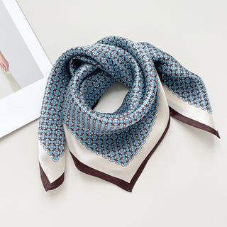 Sky blue silk scarf with brown geometric lattice pattern, cream border, and brown trim, elegantly folded to show shimmering texture