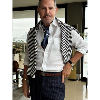 Man wearing a navy patterned silk square scarf with a white shirt, striped top, and navy trousers showcasing a refined, smart causal look.
