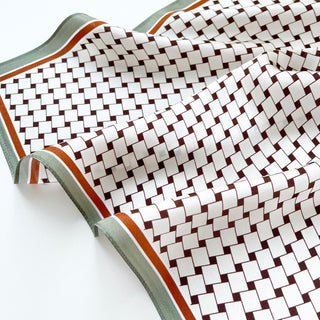 Luxurious silk scarf with white and burgundy geometric square pattern, featuring mint green and orange border trim, showing elegant drape and texture