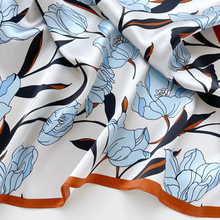 Close-up of a women’s silk bandana scarf 53cm with tulip floral print, double-sided satin square with burnt orange border by LuluLane