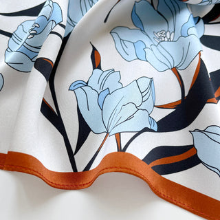 Close-up of a women’s silk bandana scarf 53cm with tulip floral print, double-sided satin square with burnt orange border by LuluLane