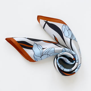 Close-up of a women’s silk bandana scarf 53cm with tulip floral print, double-sided satin square with burnt orange border by LuluLane