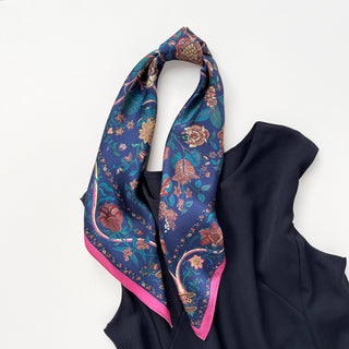 Blue vintage silk scarf with colorful floral pattern featuring pink, gold and teal blooms, bordered with pink trim, draped on black garment