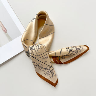 Beige silk bandana scarf with black line art cityscape pattern and brown border, displayed elegantly folded on white surface