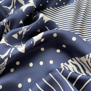 Navy silk scarf with elegant cream patterns featuring floral motifs, polka dots, and stripes in a luxurious Urban Safari design