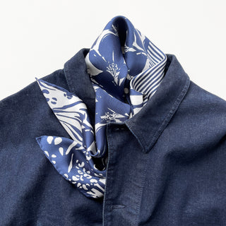 Navy Urban Safari silk scarf with white floral and animal print patterns elegantly styled on a denim shirt collar, showcasing its luxurious drape