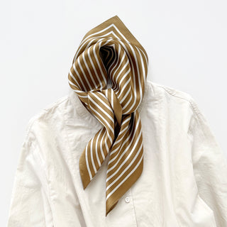 Antique brown silk bandana scarf with white striped pattern elegantly draped around collar of cream white blouse